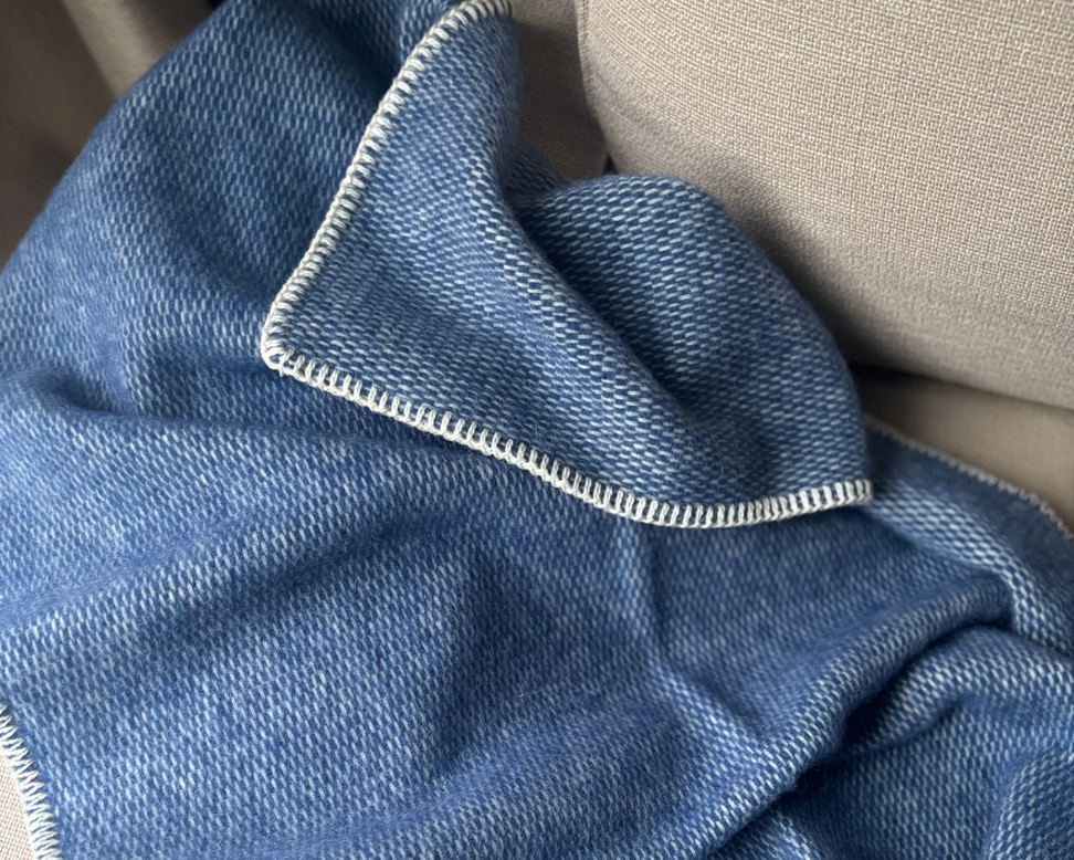Deze effen geweven wiegendeken in de warme kleur blauw is gemaakt van 100% pure new wool