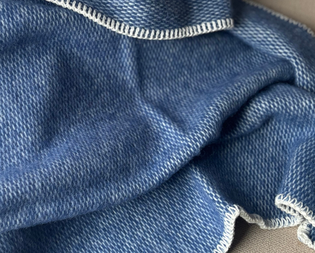 Deze effen geweven wiegendeken in de warme kleur blauw is gemaakt van 100% pure new wool.